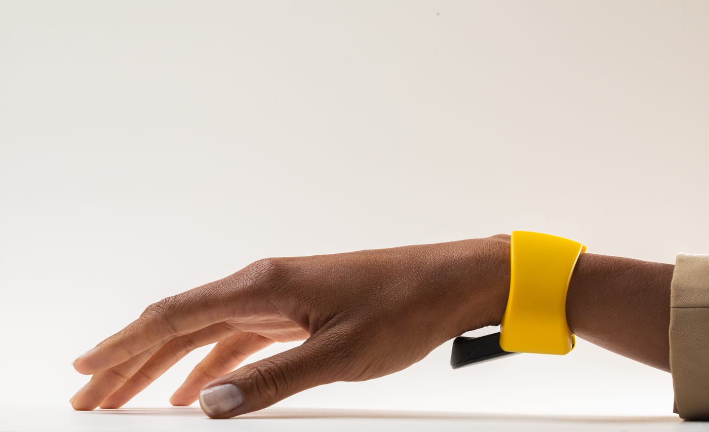 A relaxed hand on a flat surface, wearing the yellow TapXR wristband